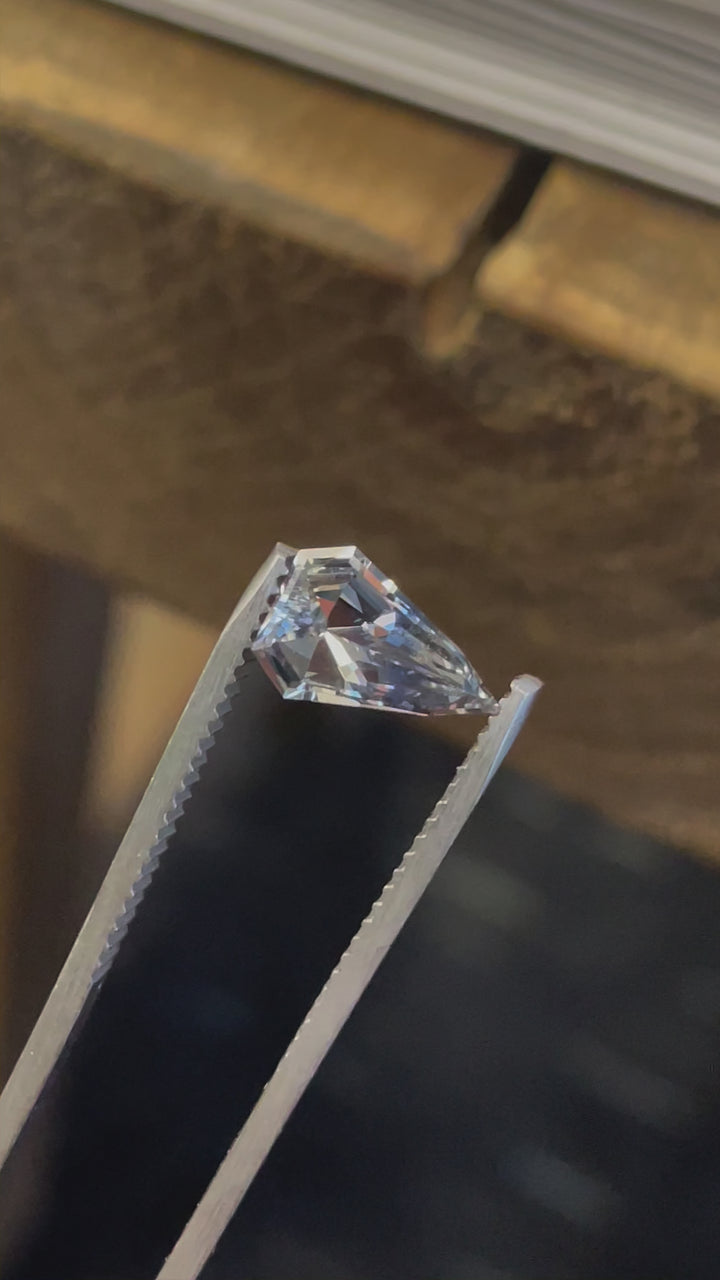 A rotating view of a 1.50-carat shield-shaped sapphire with gray, blue, and yellow hues, highlighting its intricate step cut.