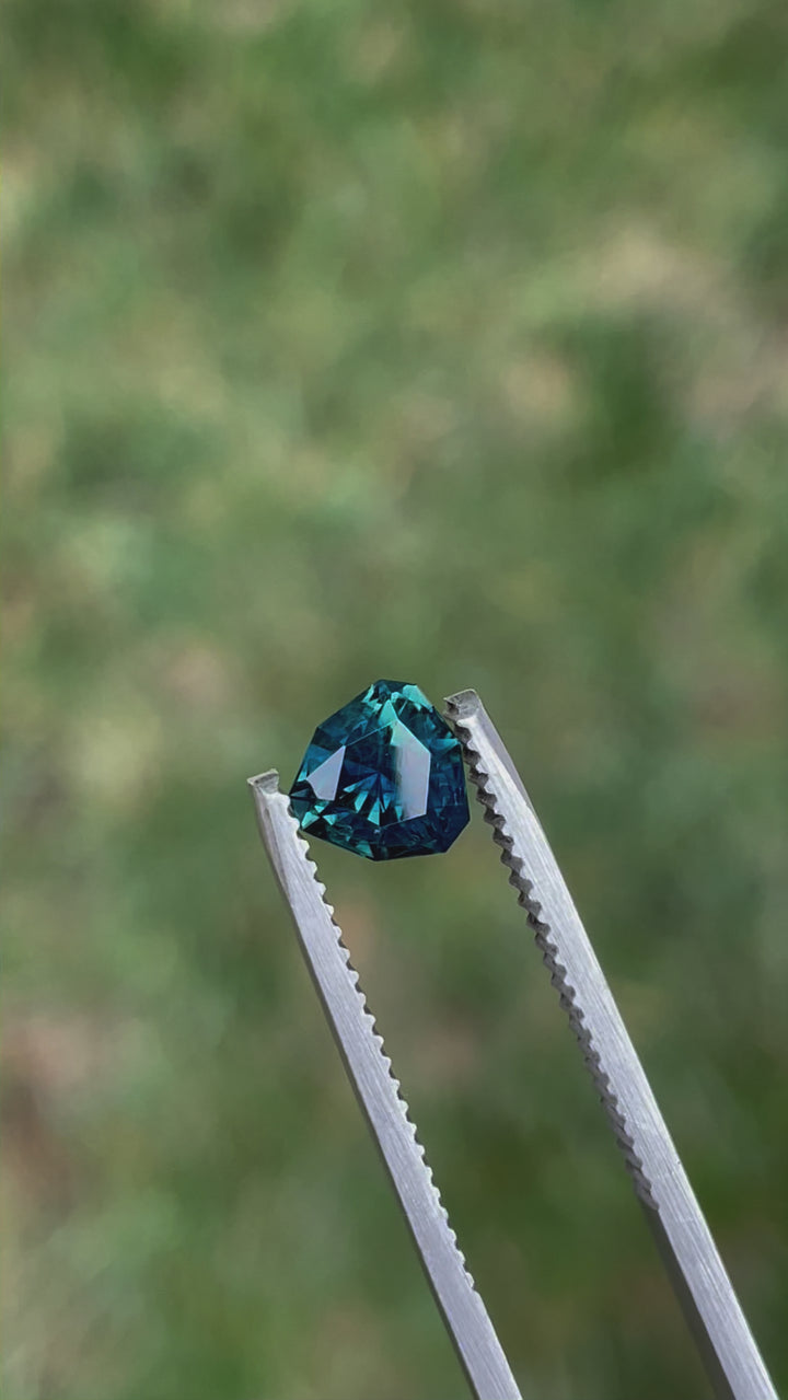 Video showcasing a 1.43-carat no-heat sapphire, cut in a custom geometric trillion shape. The gemstone flashes rich teal and blue-green tones as it moves under natural light. Originating from Madagascar, this sapphire is untreated and valued at $1,072.50.