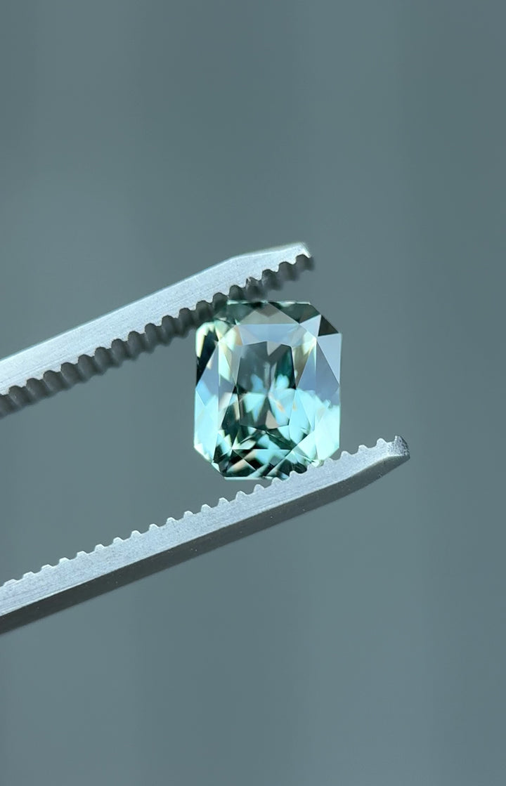 Rotating view of natural 2.53CT radiant cut sapphire showing dramatic color change between blue-green and violet-grey tones, unheated gem from Madagascar.