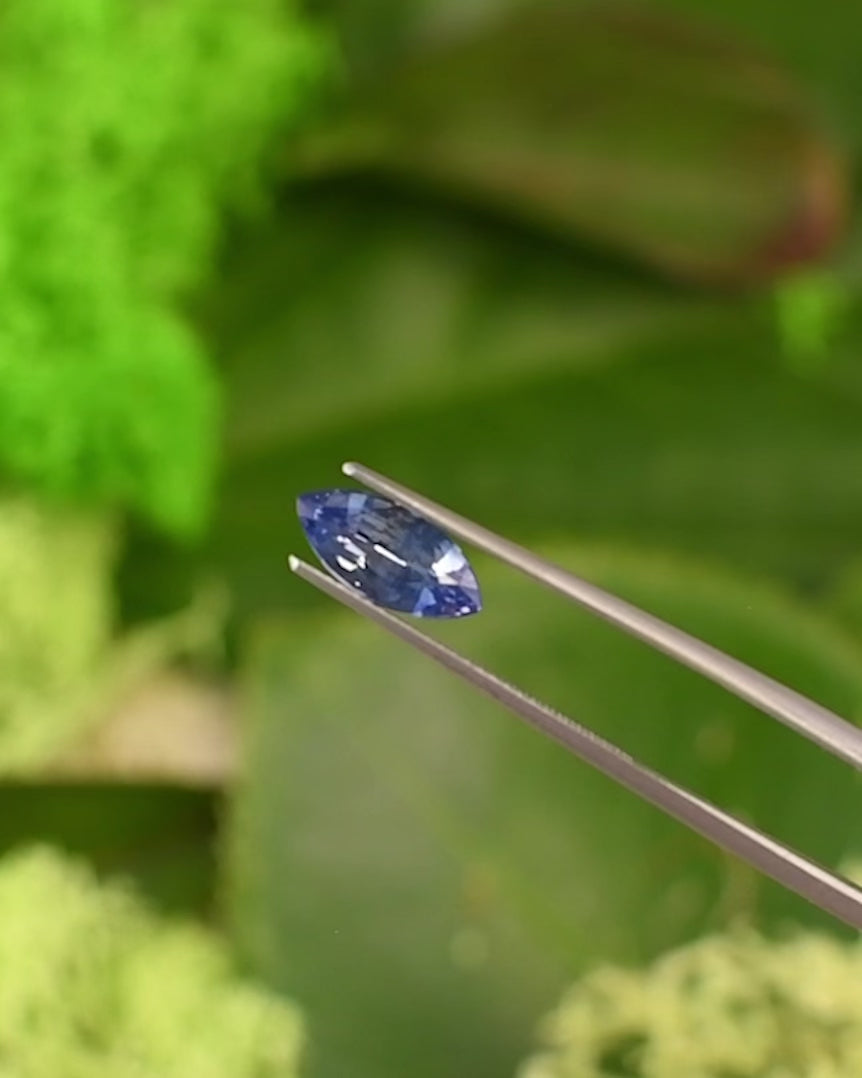 Macro video of 1.57CT vivid blue sapphire rotating in gemstone tweezers under natural sunlight, showing vibrant color play, clarity, and fine craftsmanship of the precision marquise mixed cut, unheated sapphire from Sakaraha, Madagascar.
