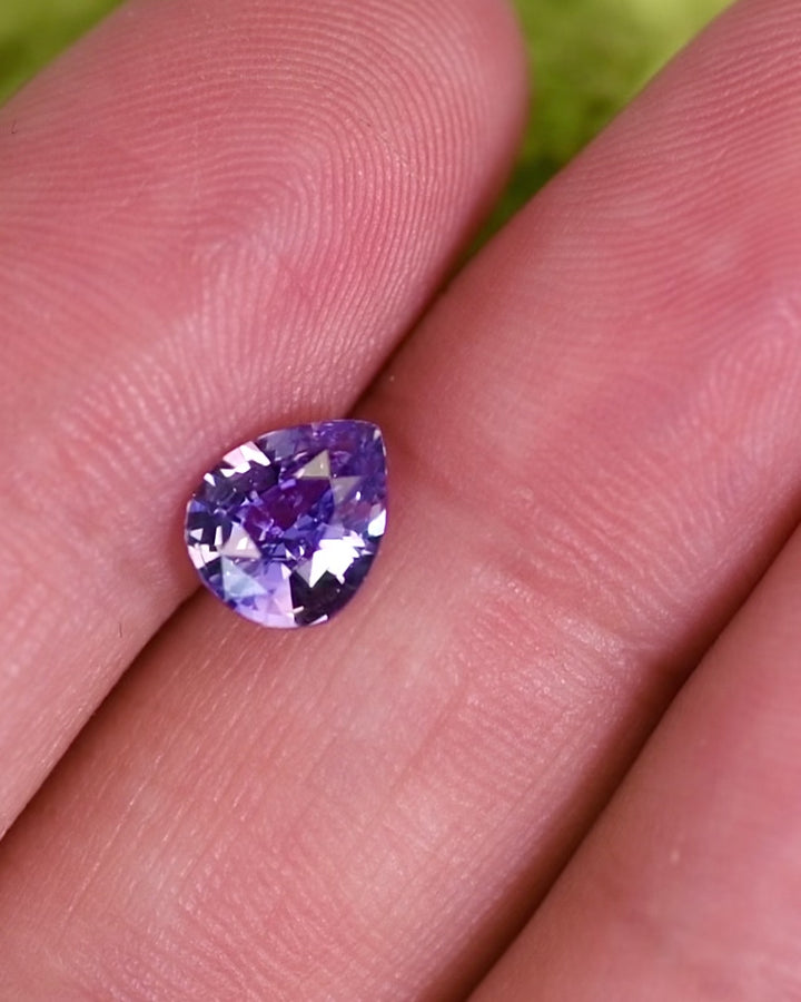 Video of 1.51 carat violet pink sapphire shown on fingertip under natural light, highlighting the gem’s sparkle, clarity, and pear brilliant cut, untreated sapphire from Sakaraha, Madagascar.