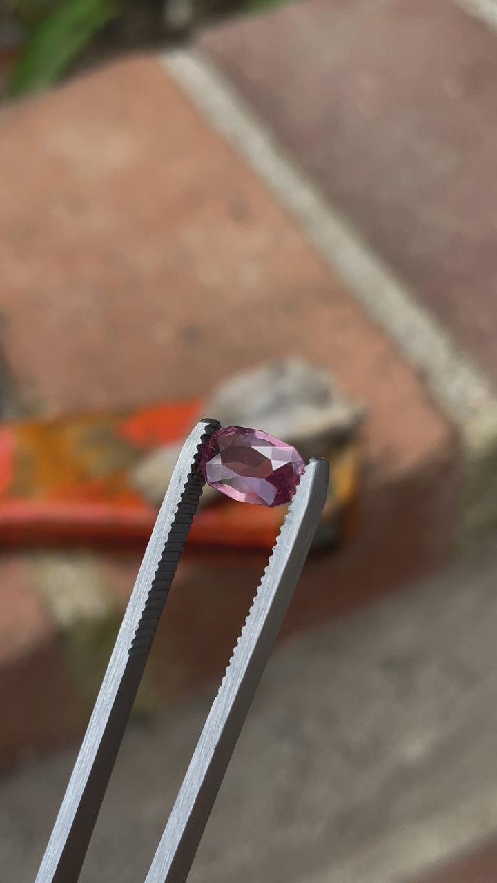 A 1.45-carat pastel grapefruit sapphire, photographed from a top perspective, showcasing its custom elongated cushion cut and serene pink-peach color tones.