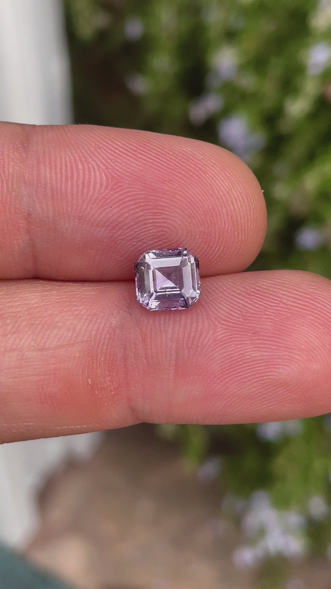 A 360-degree view of a 2.60-carat modified Asscher cut sapphire, revealing the rich purple and pink hues of the untreated stone. The video emphasizes the precision of the gem's facets and light reflection. The sapphire is from Sri Lanka, measuring 7.71mm by 7.25mm by 4.97mm.