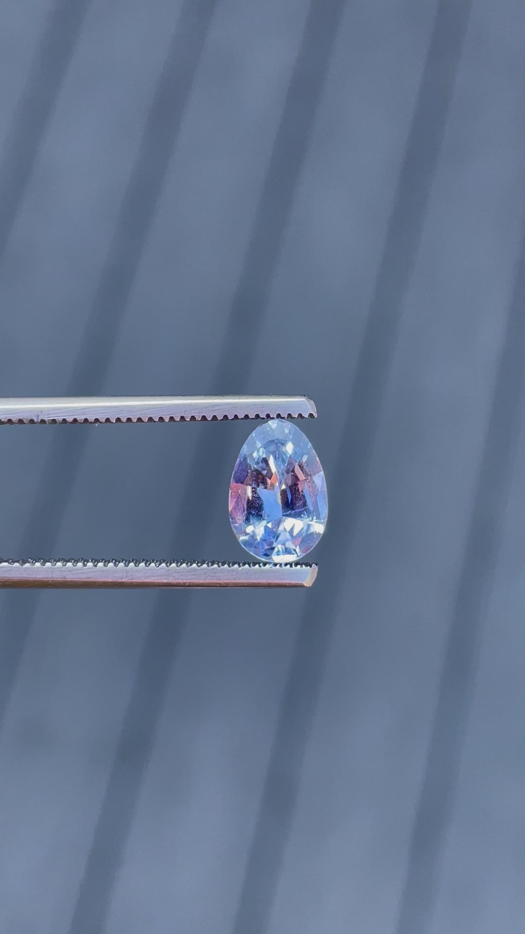 A detailed 360-degree view of a 1.74-carat Ceylon denim blue sapphire in a custom Poval cut. The video focuses on the symmetry of the gem's facets, highlighting the untreated stone's soft blue hues as it rotates. The sapphire is no-heat treated, from Sri Lanka, with dimensions of 9.18mm by 6.38mm by 3.82mm.