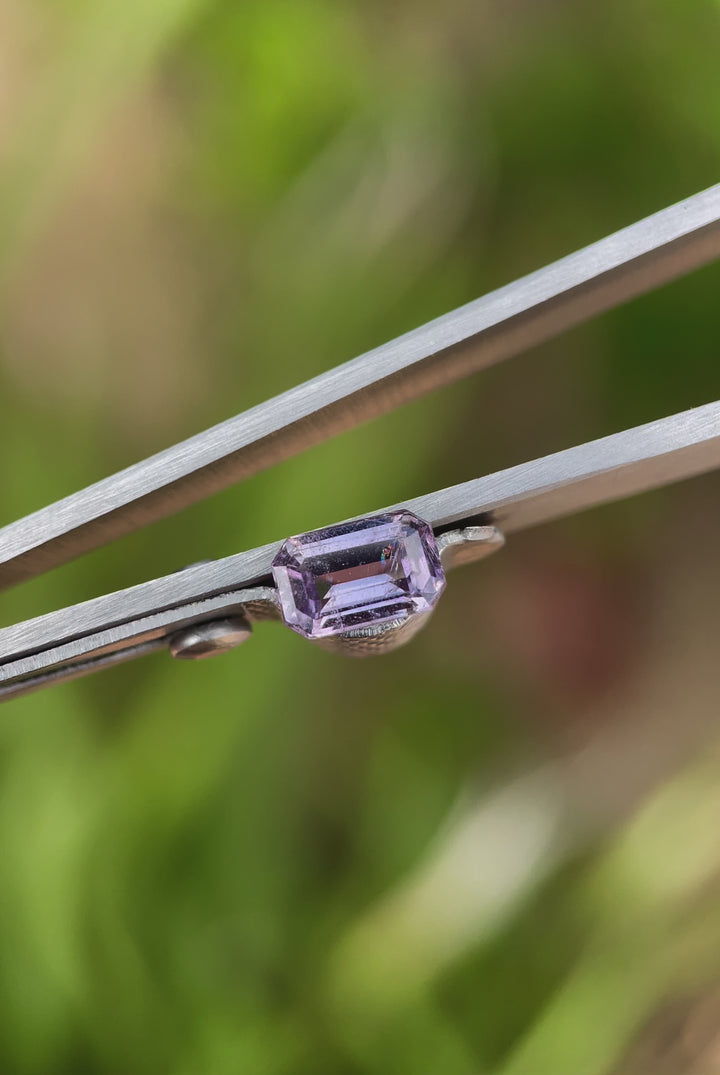 A detailed video of the 1.24-carat sapphire, displaying its subtle brown and purple tones under soft lighting. The video focuses on its precise emerald cut and intricate internal reflections.