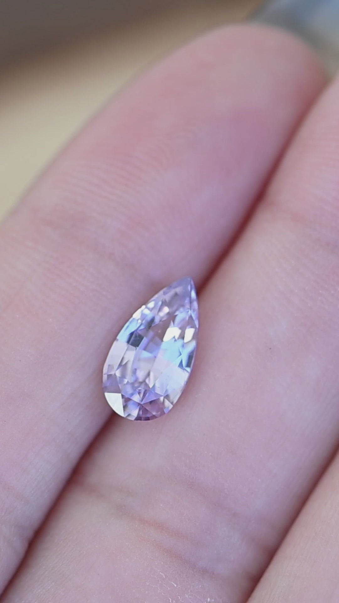 Lavender pinkish purple sapphire rotating on hand displaying sparkle, color variation, and precision pear mixed cut from Madagascar.