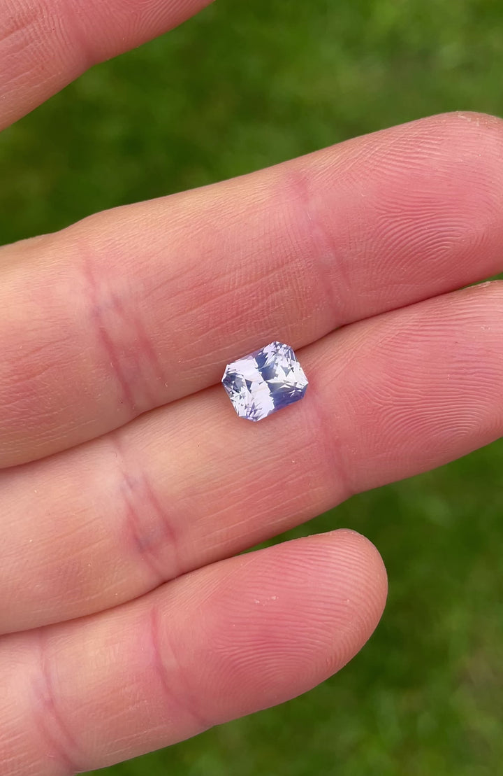 Video of a hand-rotated 2.16ct custom radiant cut sapphire in soft peach and violet tones, capturing the gem’s brilliance and clarity from Sri Lanka.