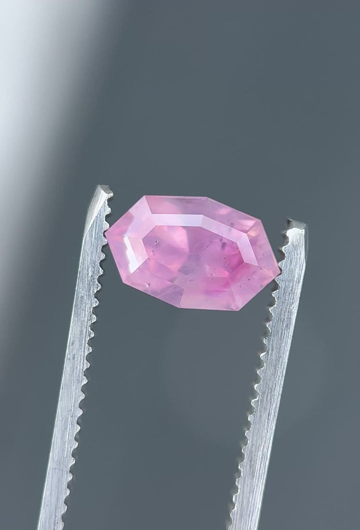 Opalescent pink peach sapphire rotating in light showing soft glow and internal silk diffusion.