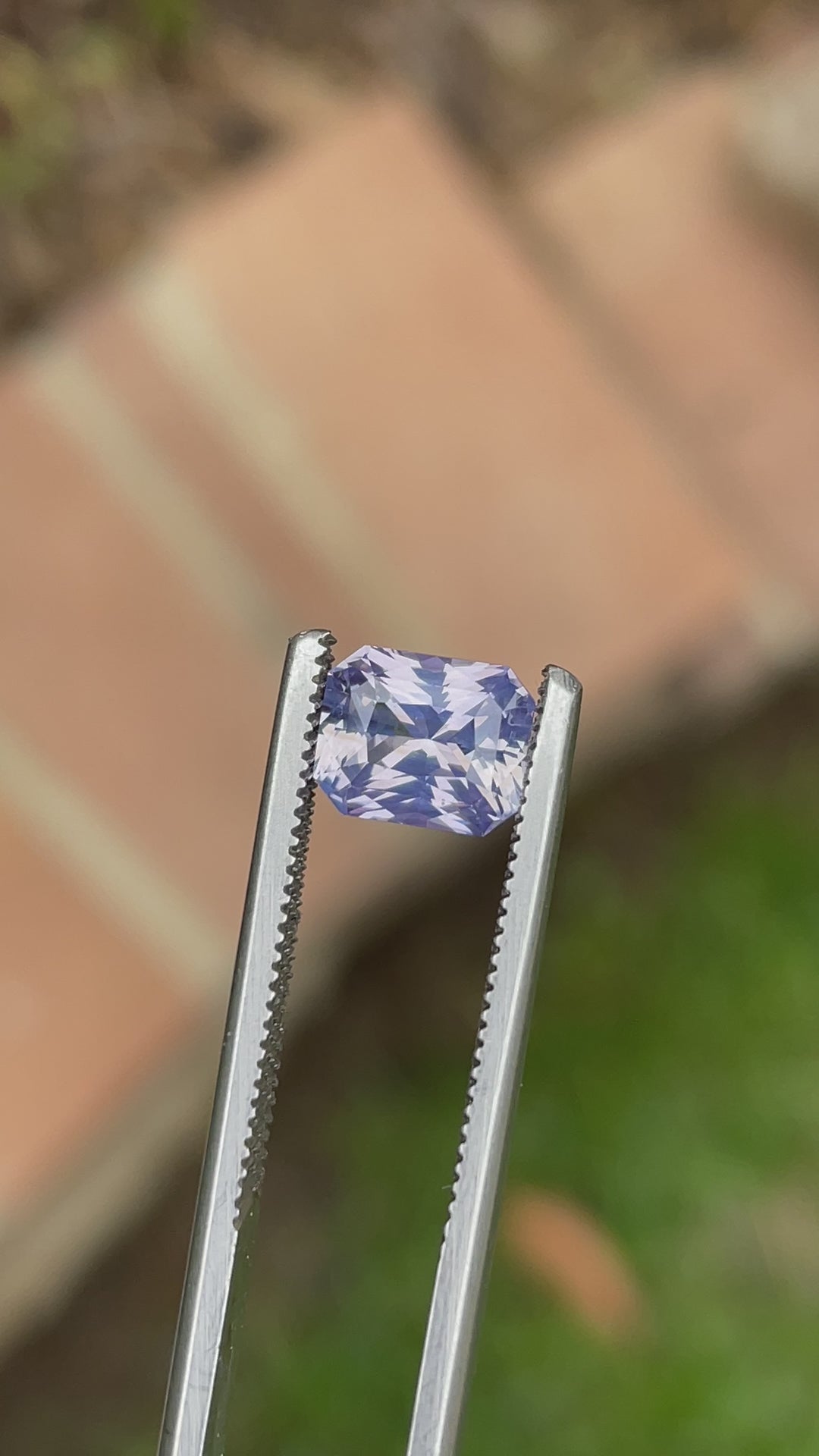 360-degree video of a 2.16-carat radiant cut sapphire from Sri Lanka, featuring shifting hues of peach, lavender, and violet under natural light.