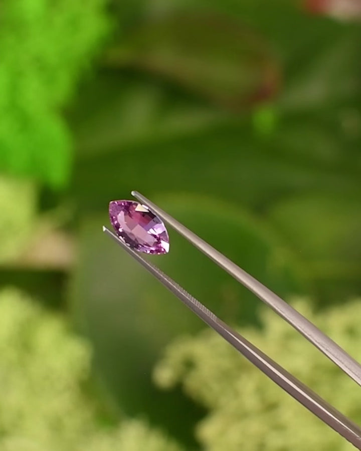 Video of 1.65CT vivid hot Barbie pink sapphire rotating in gemstone tweezers, capturing fire, brilliance, and fine facet detailing of the precision marquise mixed cut, unheated sapphire from Sakaraha, Madagascar.
