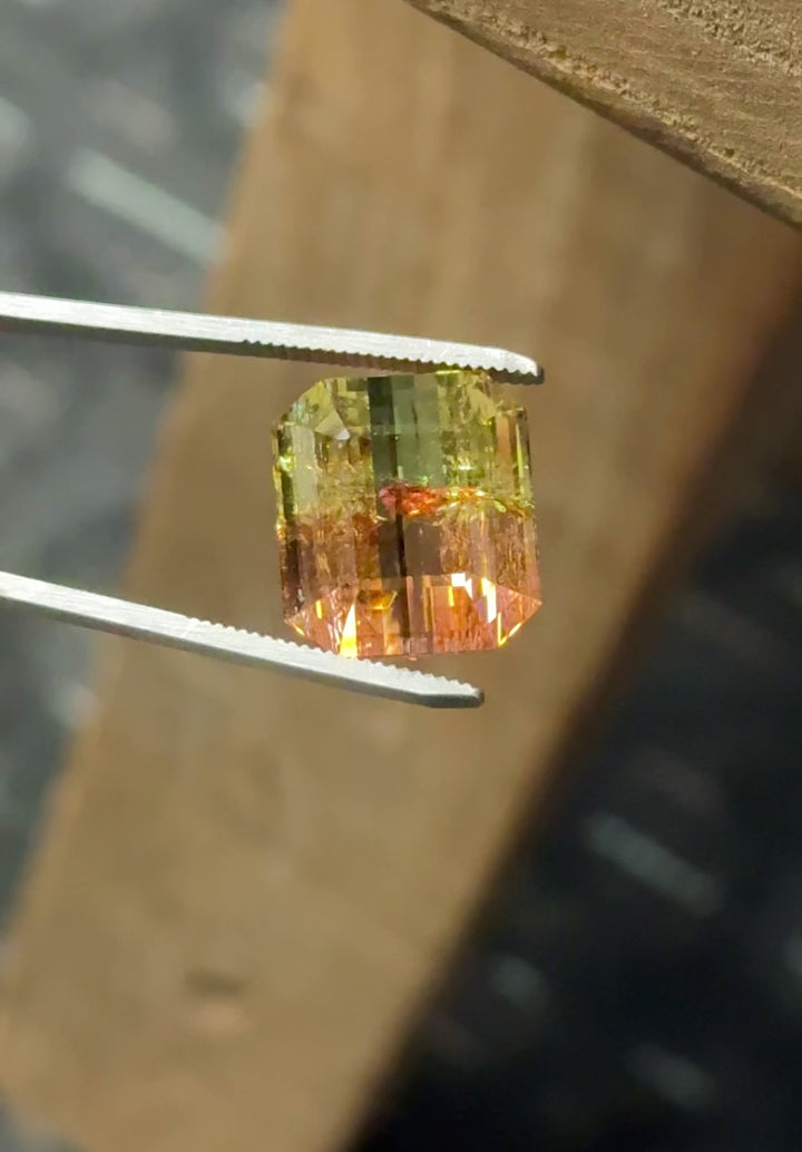 Video of 43.06ct Mozambique tourmaline rotating under light, emerald cut showing yellow green orange pink color shift and bold step cut reflections