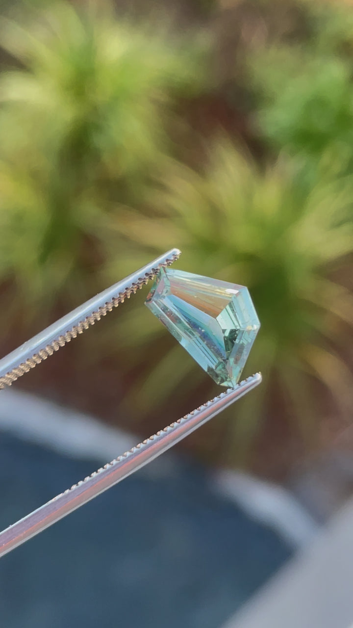 A rotating video of a 2.00-carat sapphire in a freeform geometric cut, showcasing vivid blue and green colors.