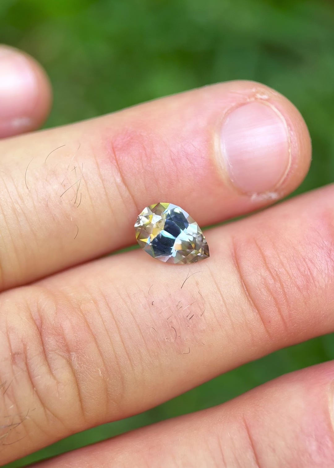 Handheld video of pear-shaped Tanzanite reflecting multicolor brilliance and sparkle from different angles
