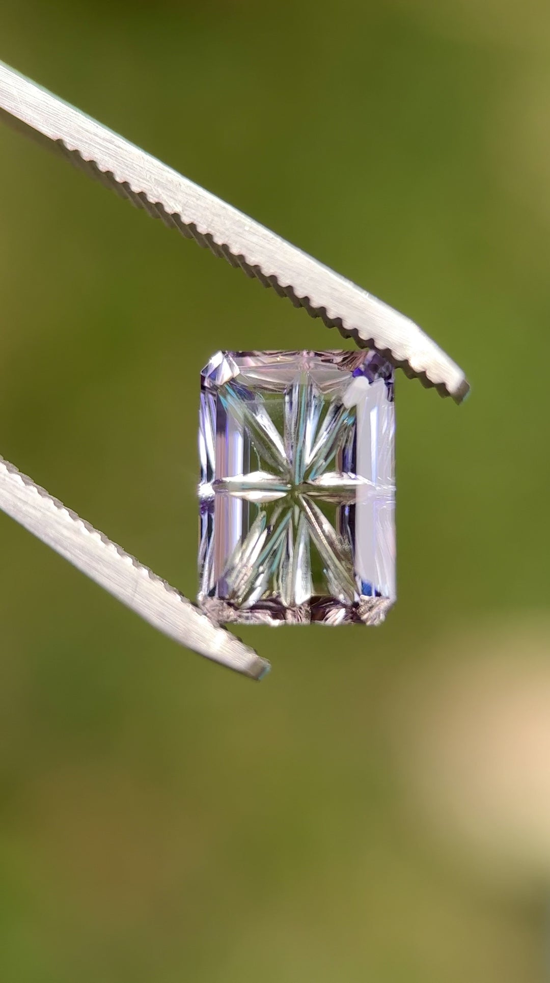 Video of a 4.01 carat multi-color Tanzanite shifting between blue, pink, and purple as it rotates, showing the custom concave fantasy emerald cut and strong internal reflections. Natural untreated Tanzanite from Merelani Hills, Tanzania.