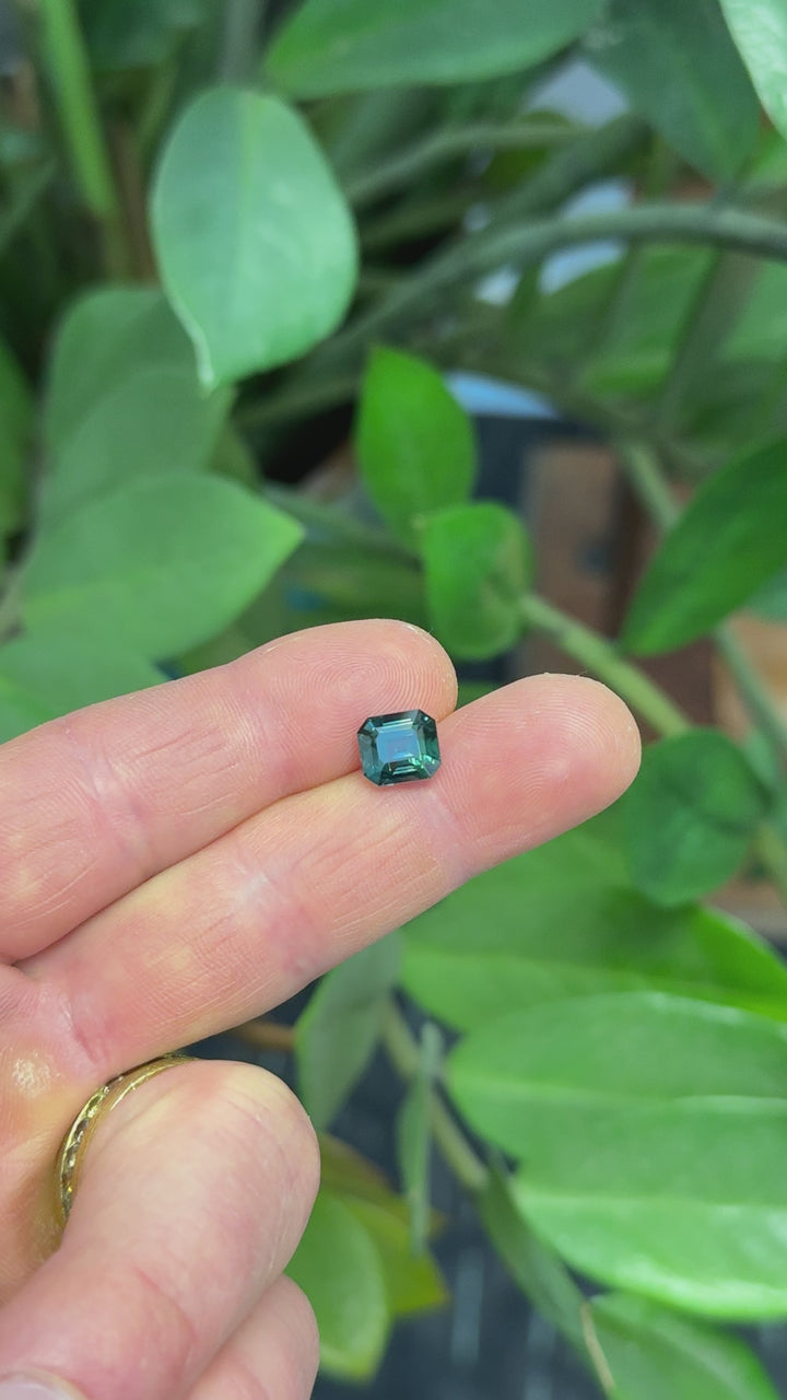 Rotating loose blue green sapphire emerald cut from Madagascar revealing rich teal tones and step-cut reflections under movement.