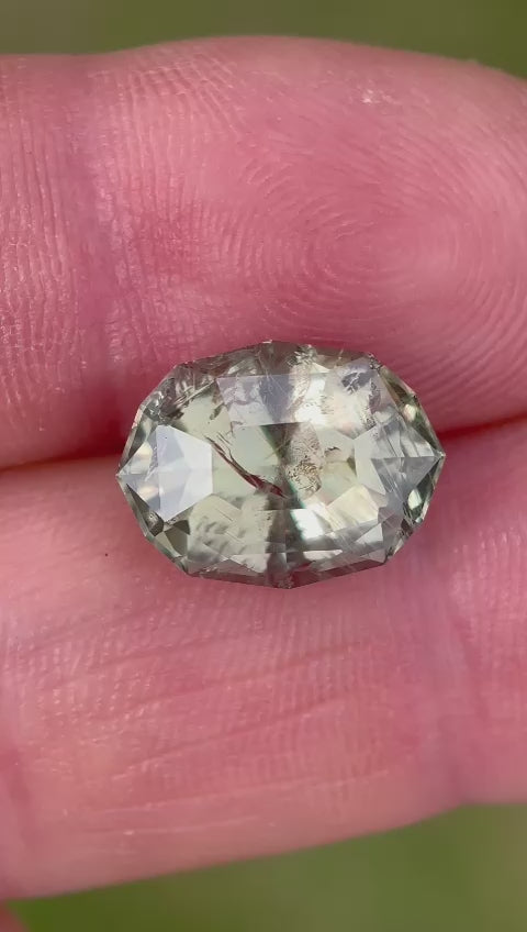 Interactive examination of a color-changing sapphire from Tanzania, demonstrating the gemstone's reaction to light and its impressive color transformation from teal blue green to greenish peach.