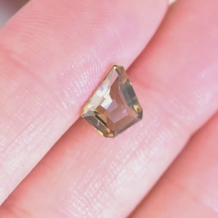 Close up video of 1.72ct Tanzanite kite cut gemstone displaying geometric faceting sparkle and golden teal yellow tones 