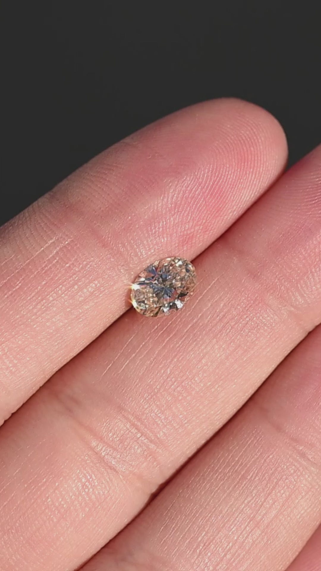 1.02ct natural champagne oval brilliant cut diamond from Canada rotating in hand under direct sunlight showing size and brilliant faceting.