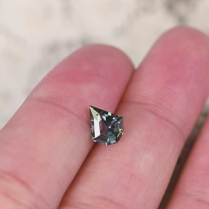 1.36 carat untreated yellow green teal Tanzanite shield cut rotating under natural light, custom geometric mix faceted gemstone from Merelani Hills Tanzania showing vivid color shift and sparkle for custom jewelry