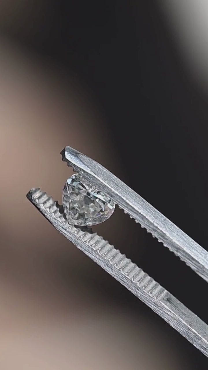 Video of a natural 1.21 carat salt and pepper heart cut diamond resting on fingertips, displaying antique-style faceting, white brilliance, and naturally occurring inclusions as it moves in natural light.