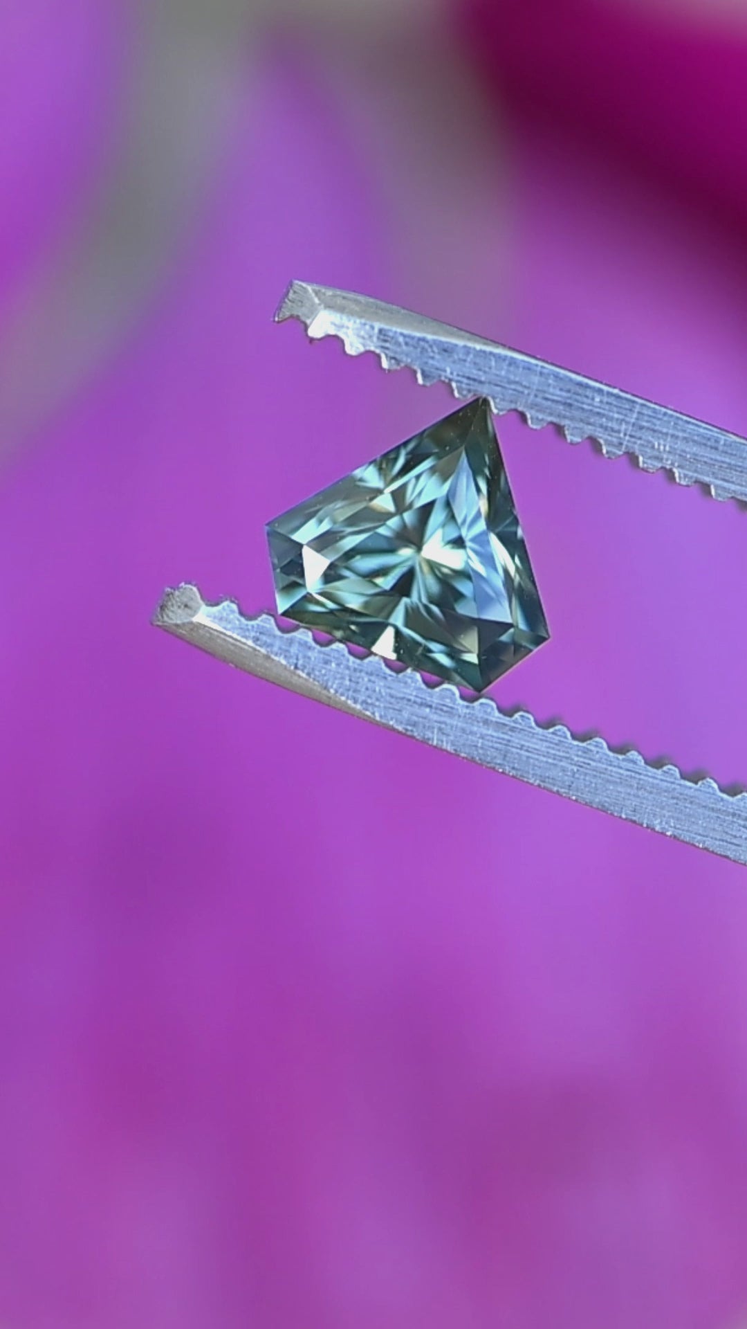 Parti blue green sapphire rotating in tweezers showing precision faceting, natural Madagascar origin, and vibrant blue-green color movement.