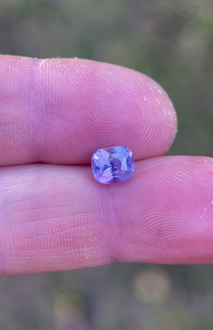 A hand-held showcase of a 2.00-carat opalescent pink and violet sapphire, demonstrating its radiant clarity and vibrant hues from different angles. Sri Lankan origin, unheated and ethically sourced.