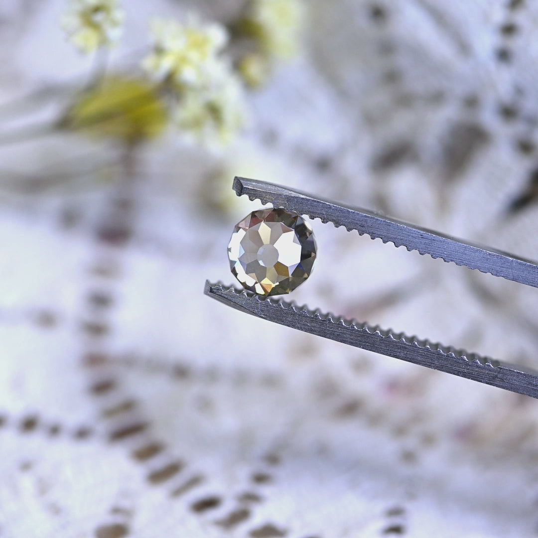 Loose 1.15 carat Mughal cut champagne diamond turning in tweezers, revealing VVS1 clarity and very strong blue fluorescence.