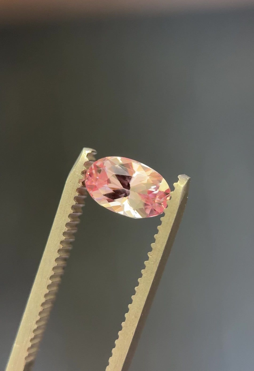 Video showcasing 1.50 carat salmon pink sapphire with vibrant color play and brilliant oval cut