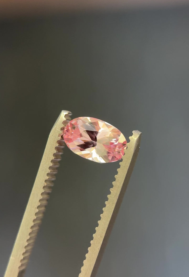Video showcasing 1.50 carat salmon pink sapphire with vibrant color play and brilliant oval cut