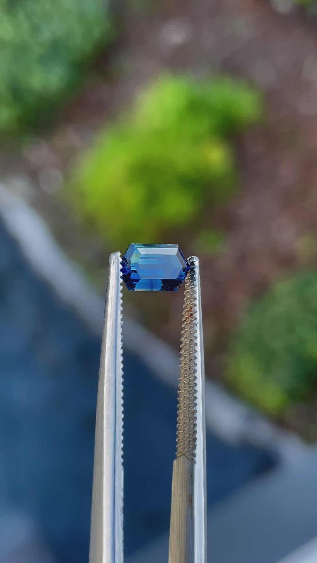 1.31-carat octagonal step-cut sapphire with deep blue, green, and teal hues from Gombe, Nigeria, showcased in natural lighting to highlight its brilliance and clarity.