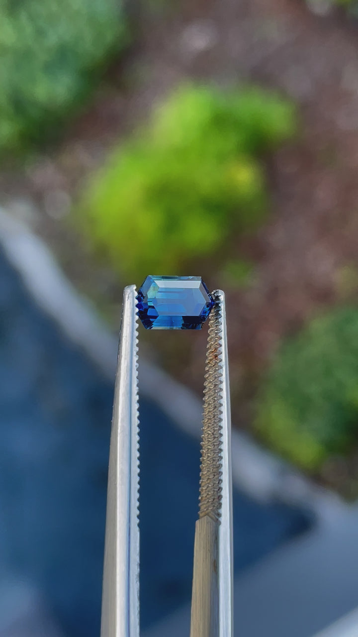 1.31-carat octagonal step-cut sapphire with deep blue, green, and teal hues from Gombe, Nigeria, showcased in natural lighting to highlight its brilliance and clarity.