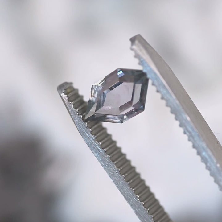 Video of 1.03ct Montana sapphire hexagon portrait cut rotating in tweezers, showing blue, purple, and gray color shift and step cut brilliance, untreated El Dorado Bar Deposit sapphire.