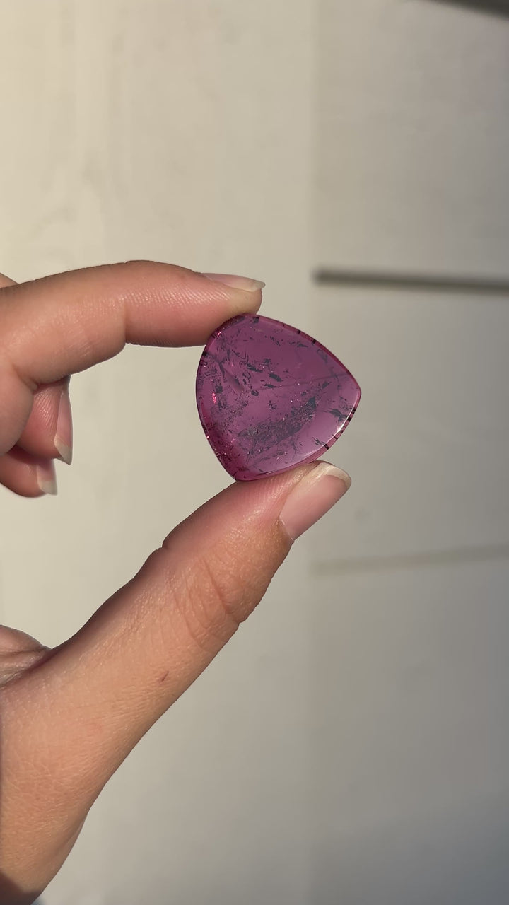 Explore the vibrant raspberry-magenta color and natural internal character of this 28.02 carat untreated pink tourmaline from Congo. Cut as a polished slice measuring 27.37 × 26.23 × 3.48 mm, the gemstone features a softly triangular silhouette and visible mineral inclusions. An expressive loose gemstone for custom pendants, statement jewelry, and contemporary one-of-a-kind designs.
