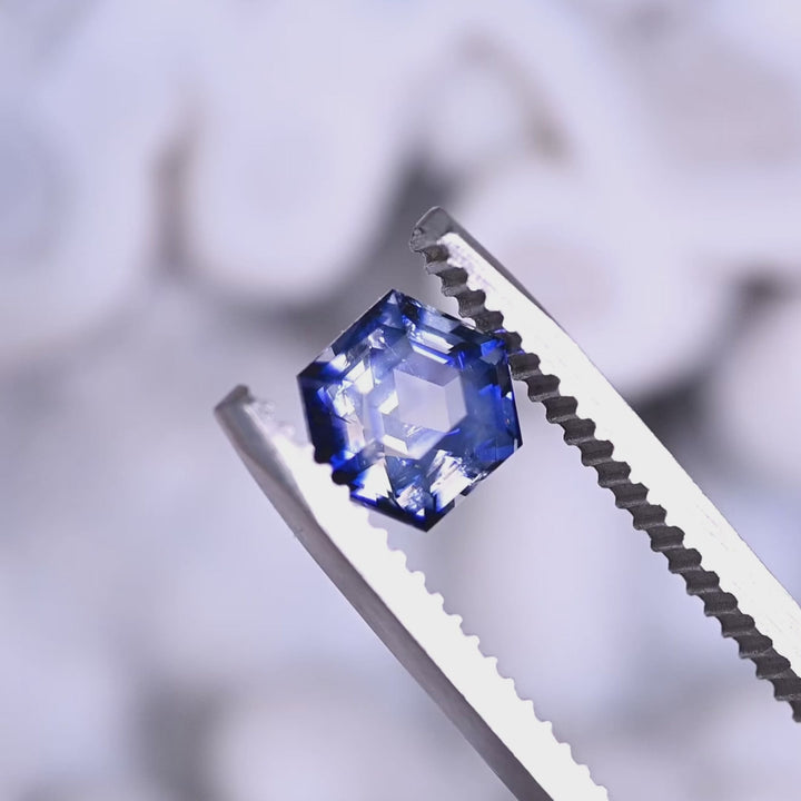 Loose blue and colorless bi‑color sapphire from Ratnapura, Sri Lanka rotating in tweezers, showing the precision hexagon step cut and the contrast between the blue and colorless zones.