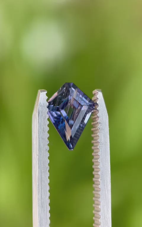 Video of a 1.37 carat parti sapphire with a custom step cut kite portrait, highlighting its striking color variations and the gem's natural sparkle under sunlight.