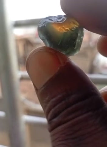 Slow-motion video of an uncut Nigerian parti sapphire rough from Gombe, showing natural orange, yellow, blue, and green color zoning prior to precision emerald cutting