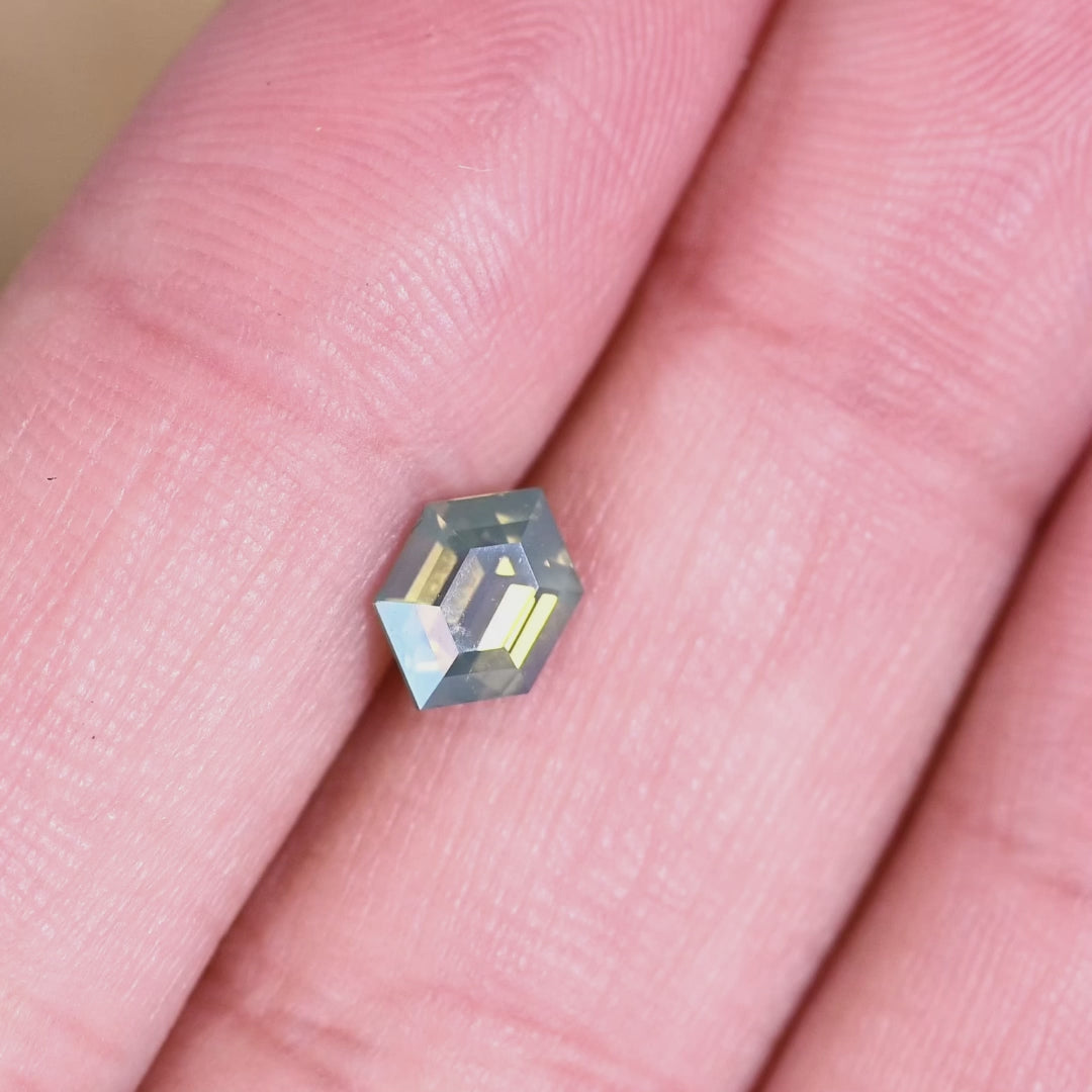 Loose opalescent green yellow sapphire from Madagascar rotating under light displaying the hexagonal step cut structure and natural color play.