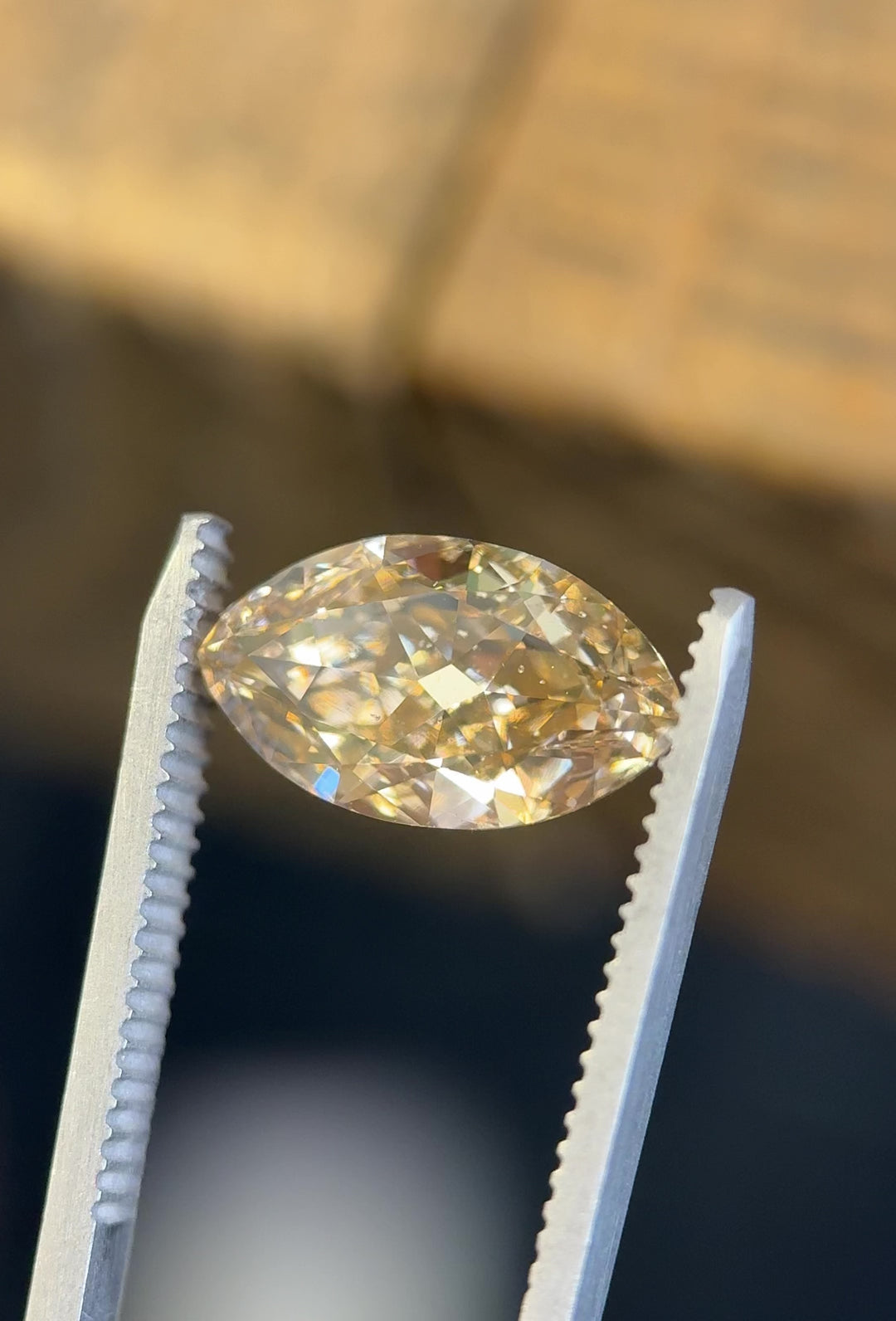 Video of a 4.01 carat rosy champagne fancy yellow brown diamond from South Africa, rotating in tweezers to display its antique moval modified brilliant cut, SI2 clarity, and natural warm tones under daylight.