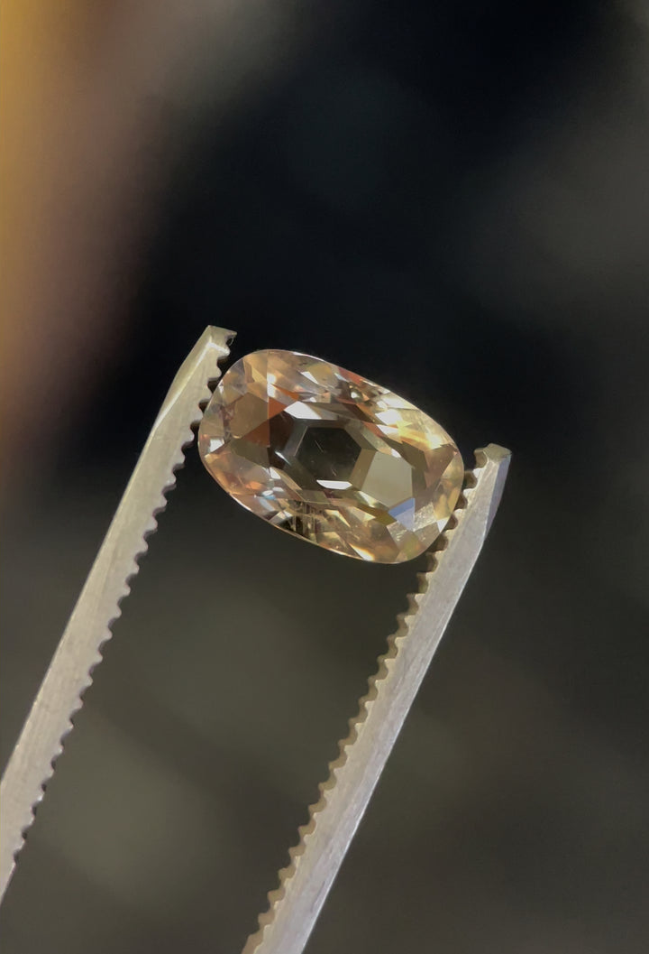 A stunning 2.29-carat sapphire with modified cushion cut, showcasing yellow, teal, and green hues. The gem's brilliance and clarity are displayed as it catches the light from multiple angles. Origin: Umba River, Tanzania.