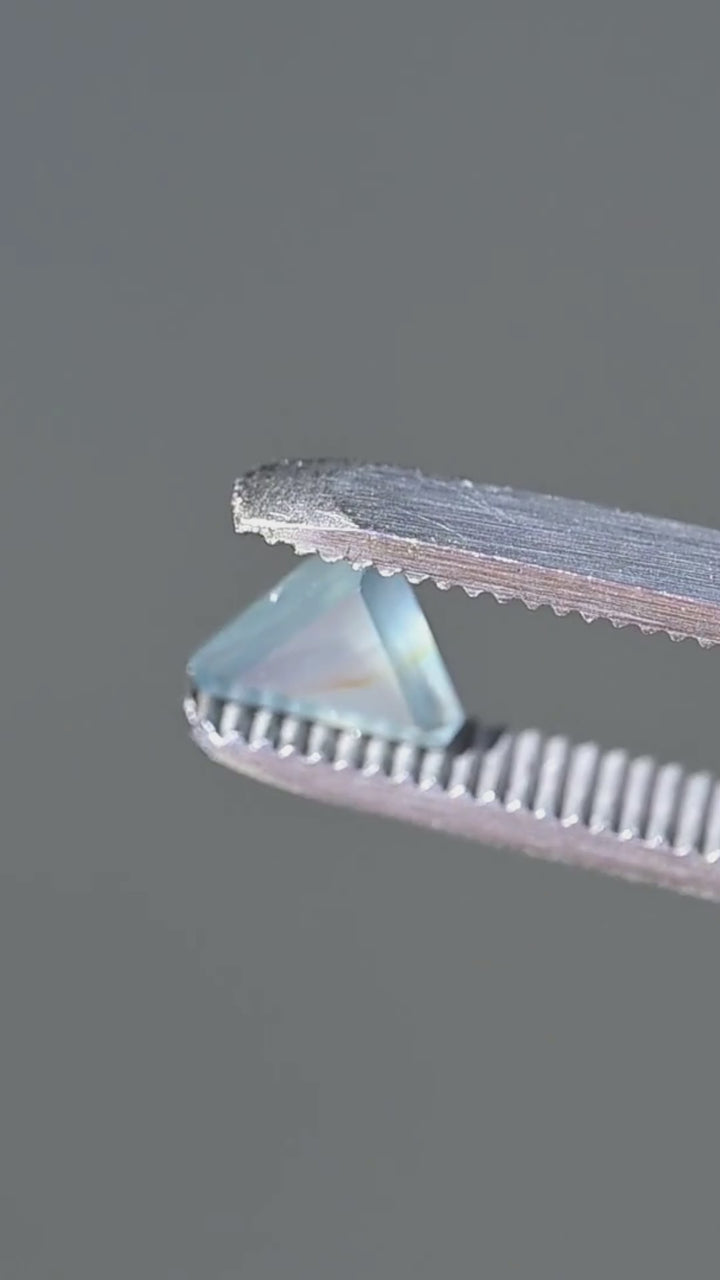 A close-up view of the precision trillion cut, pale blue-green opalescence and delicate natural inclusion of this untreated 1.15ct Nigerian sapphire.