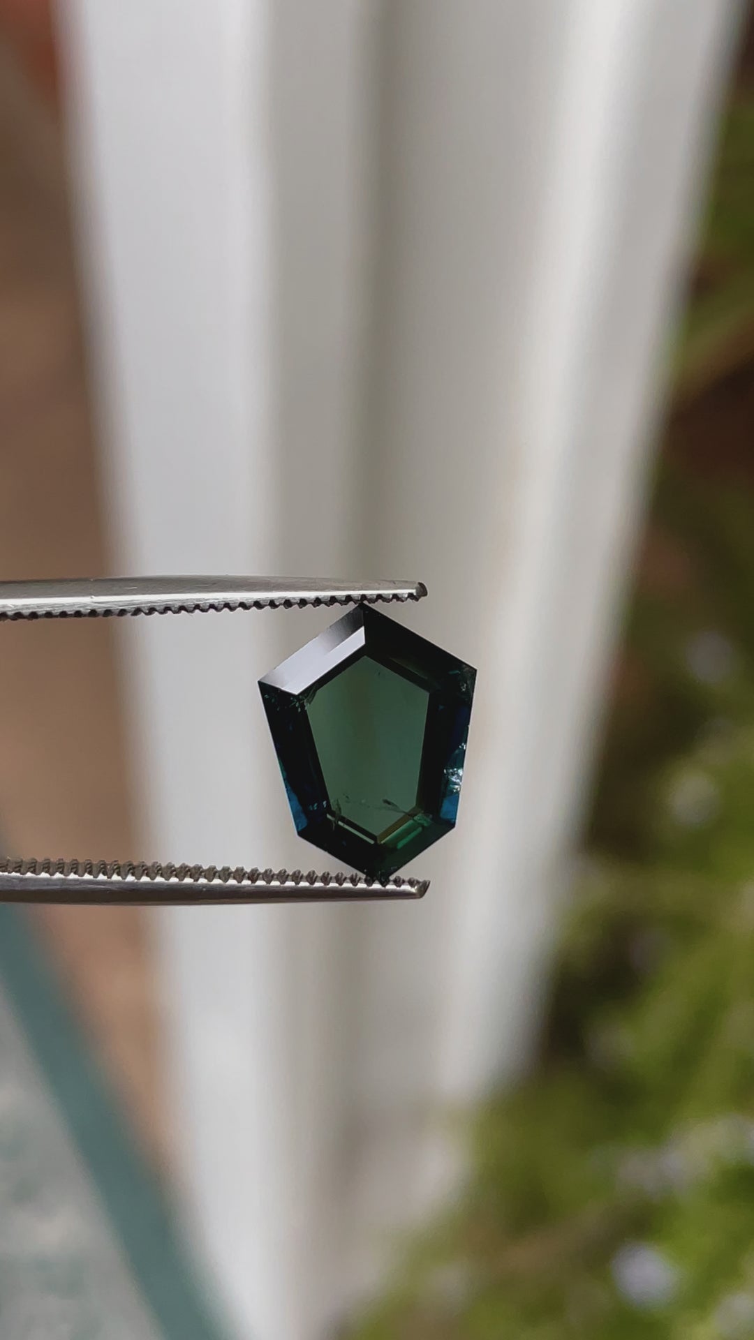 A 360-degree view of a 3.77-carat sapphire with a custom shield portrait cut. The video emphasizes the rich peacock, teal, blue, and green tones of the gemstone as it rotates, showcasing the precision of its facets. The stone is untreated, sourced from Garba Tula, Kenya, and measures 12.54mm by 9.29mm by 3.02mm.