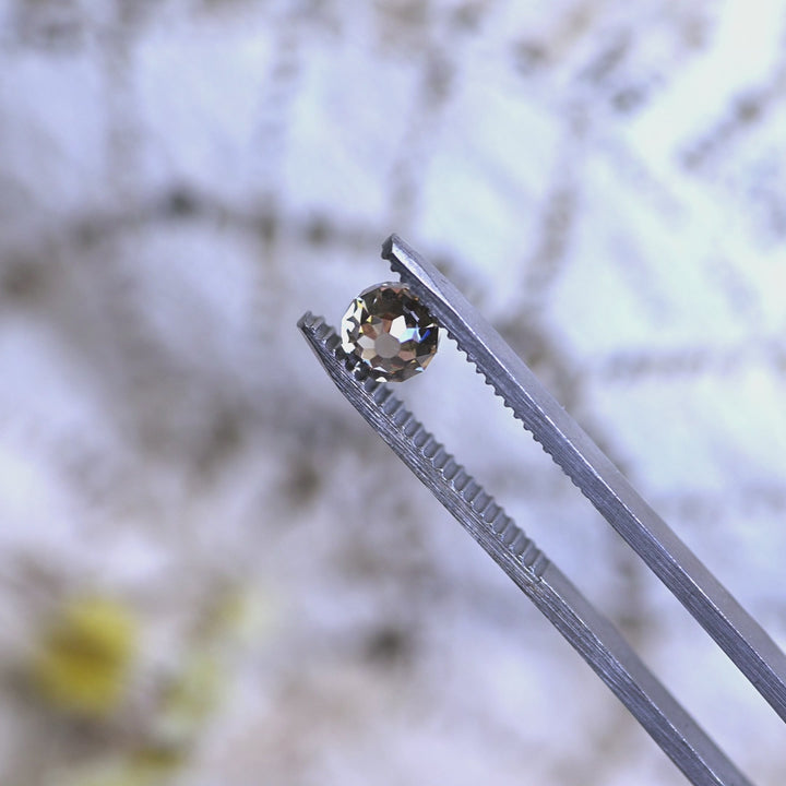Loose fancy yellow brown Mughal cut diamond from South Africa rotating in tweezers, showcasing its symmetry, sparkle, and antique-inspired cut.