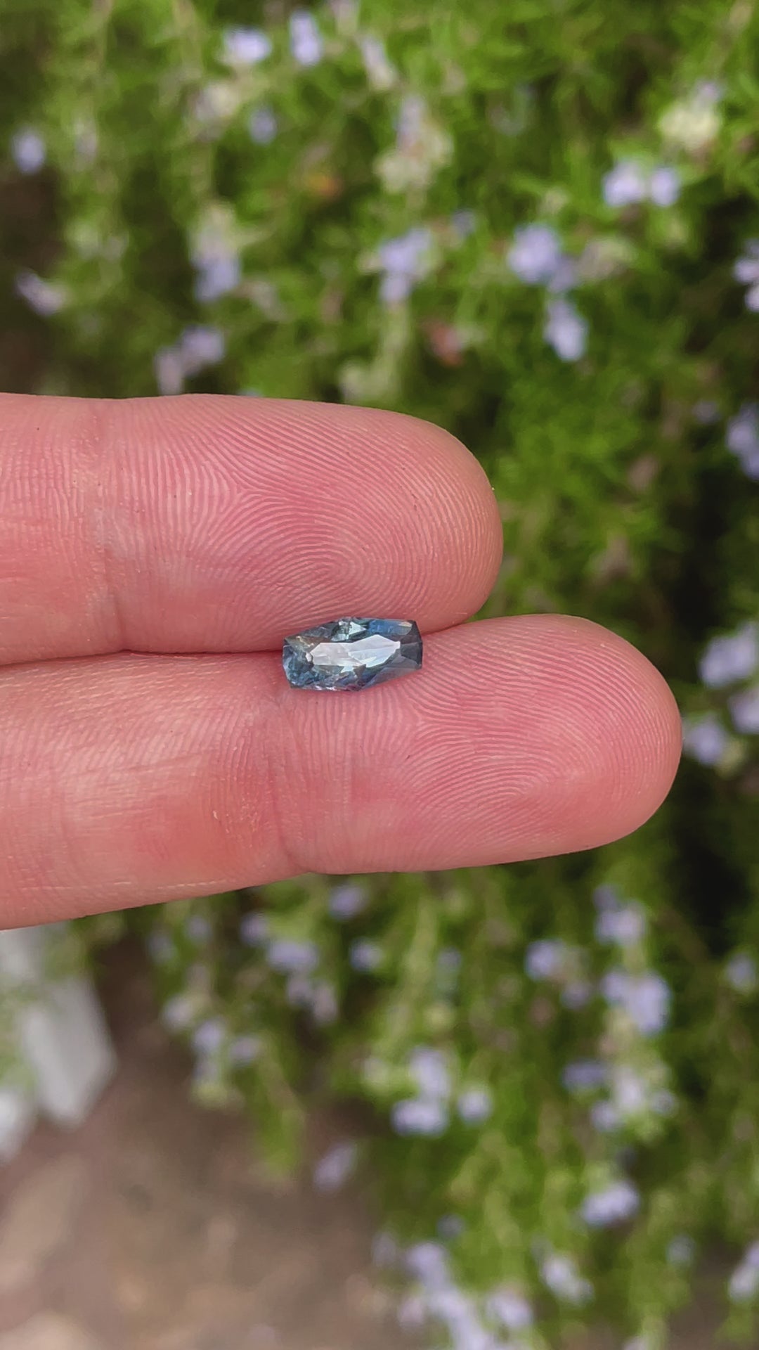 A 360-degree view of a 2.14-carat denim blue sapphire with a custom geometric elongated cushion cut. The video showcases the brilliance and color of the gemstone as it rotates, highlighting the precision of its cut. The stone is untreated, sourced from the Umba River, Tanzania, and measures 10.66mm by 5.55mm by 4.17mm.