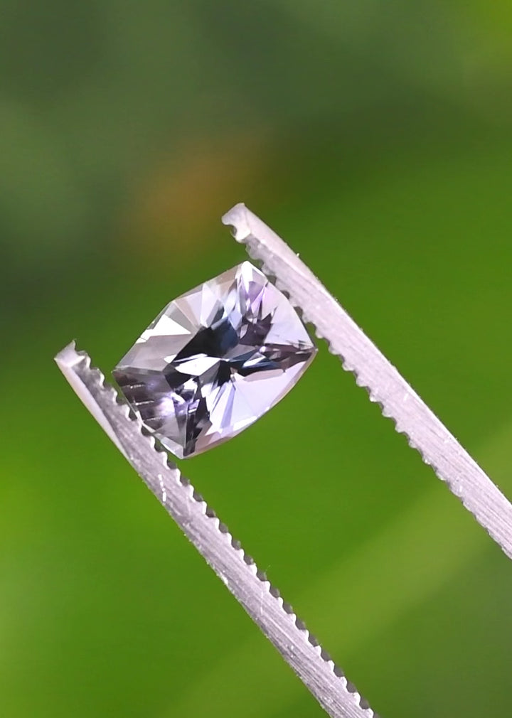 Video of a 1.54 carat untreated mermaid tanzanite rotating in tweezers, revealing purple, blue, and green color play in a custom mix cushion cut from Merelani Hills, Tanzania.