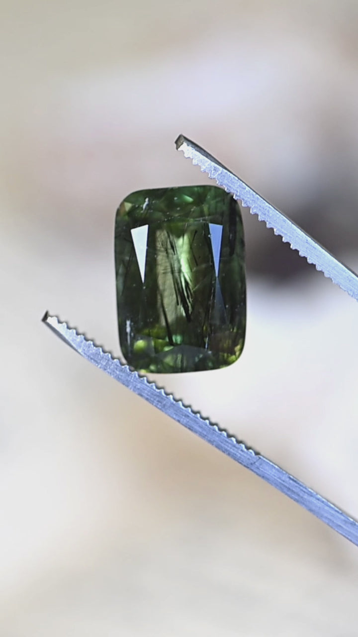 View this exceptional untreated Pakistani peridot in hand as its deep forest-green color, modified radiant cut, and remarkable natural crystal inclusions come to life from every angle.