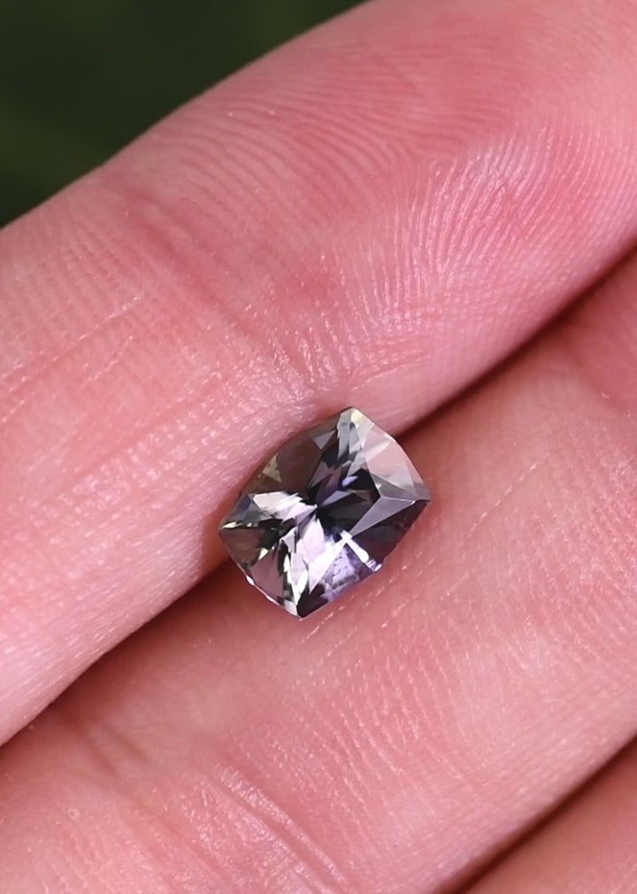 Macro video showing light movement across an untreated 1.54CT mermaid tanzanite, highlighting the custom mix cushion facets and vibrant purple blue green hues from Tanzania.