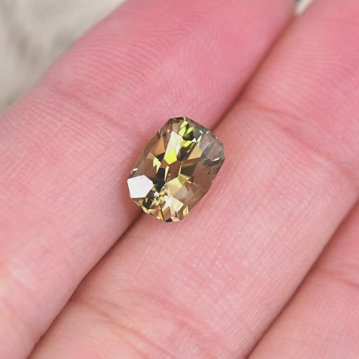 2.59 carat untreated green yellow Tanzanite geometric cushion cut rotating under natural light, Merelani Hills Tanzania gemstone showing brilliance, color shift and precision faceting for custom jewelry