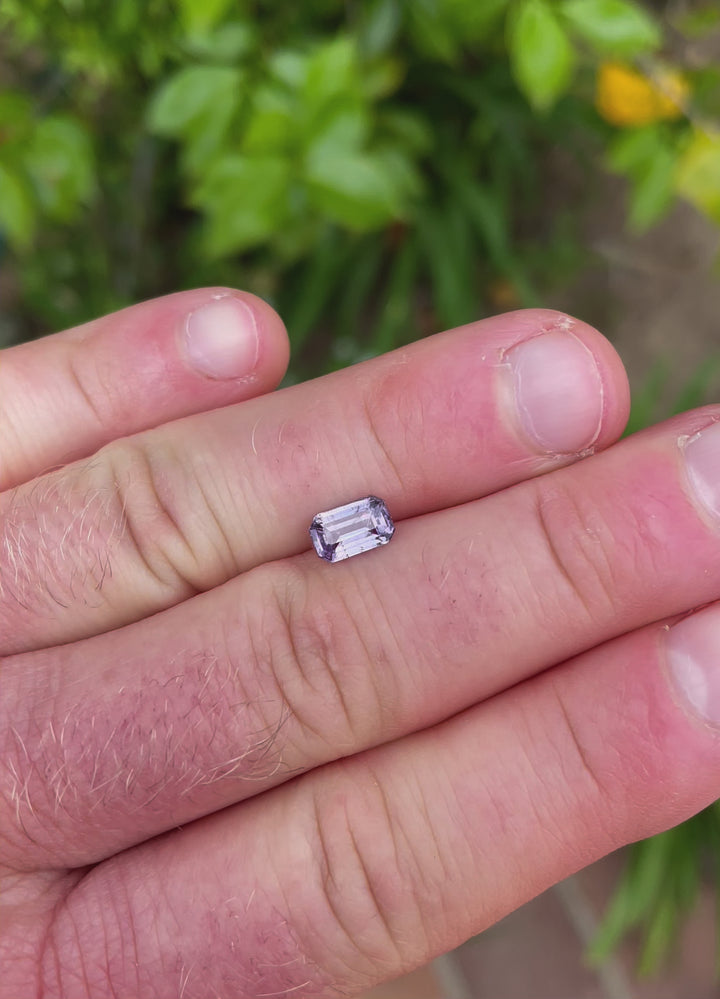 A video presenting the sapphire's full dimensions, weight, and color. The stone reveals its brown and purple shades with clean edges and a smooth, modified emerald cut.