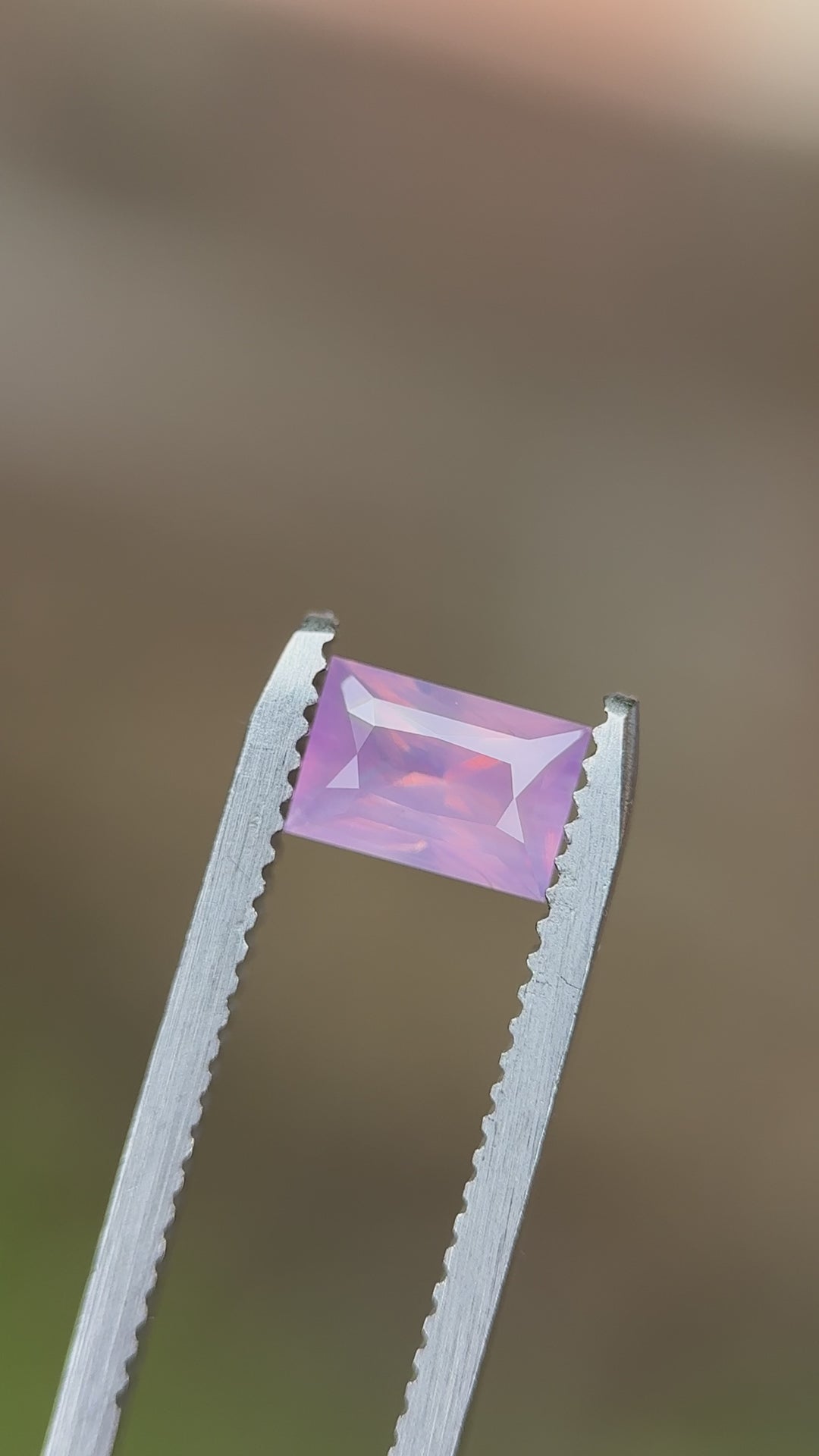 Rotating view of a 1.20-carat blush pink opalescent sapphire from Sri Lanka in a baguette mixed cut, showcasing light reflection and clarity.