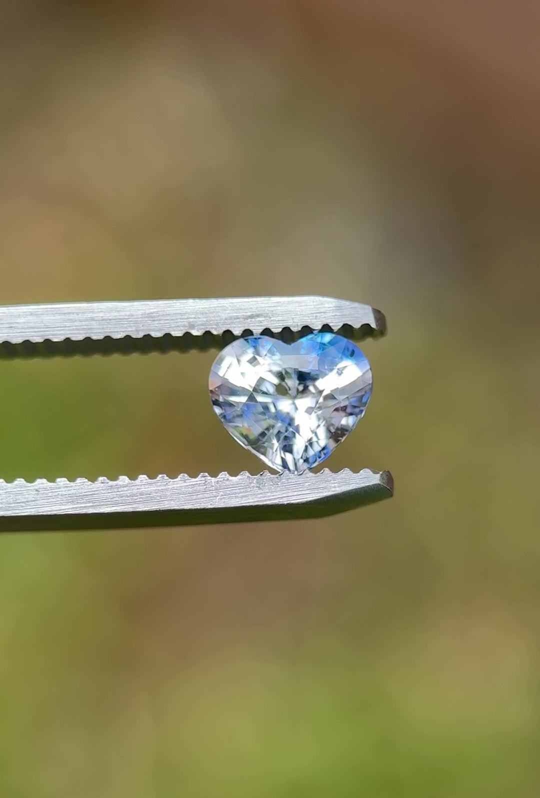 Close-up video of a heart cut parti sapphire rotating in tweezers, reflecting brilliant blue and clear color zoning – 1.30ct heated gem from Sakaraha, Madagascar.